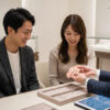 銀座のジュエリーショップで婚約指輪を試着し、笑顔を見せる日本人カップルと専門コンシェルジュの接客風景