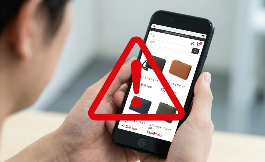 スマートフォンでバルコスの偽サイト（極端な値引きや不審な支払方法）に遭遇し、警告マークが表示されているイメージ。ネット購入時の注意を喚起