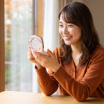 秋の光の中で、新作コスメ（スノービューティー）のコンパクトを嬉しそうに眺める日本人女性
