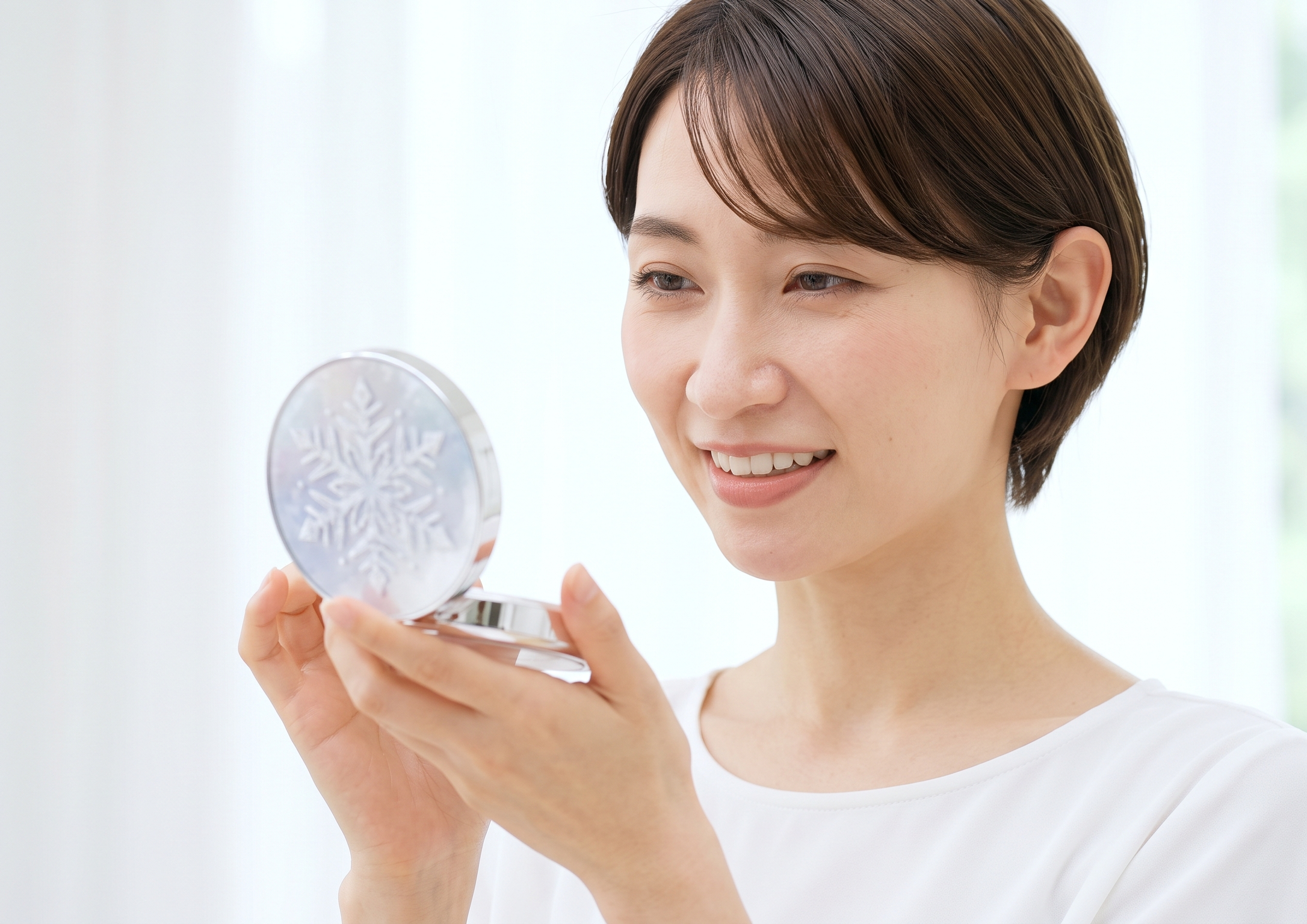 雪の結晶デザインのコンパクトを手に持ち、興味深く見つめる日本人女性