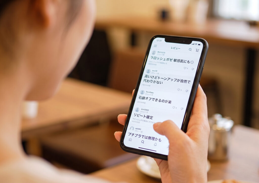 カフェでスマートフォンを操作し、Qoo10メガ割やセールの情報を確認している日本人女性